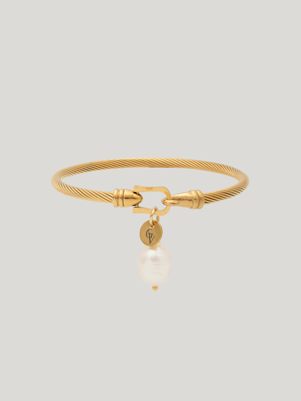 Gold ALEXA bangle bracelet with a dangling freshwater pearl on a light background